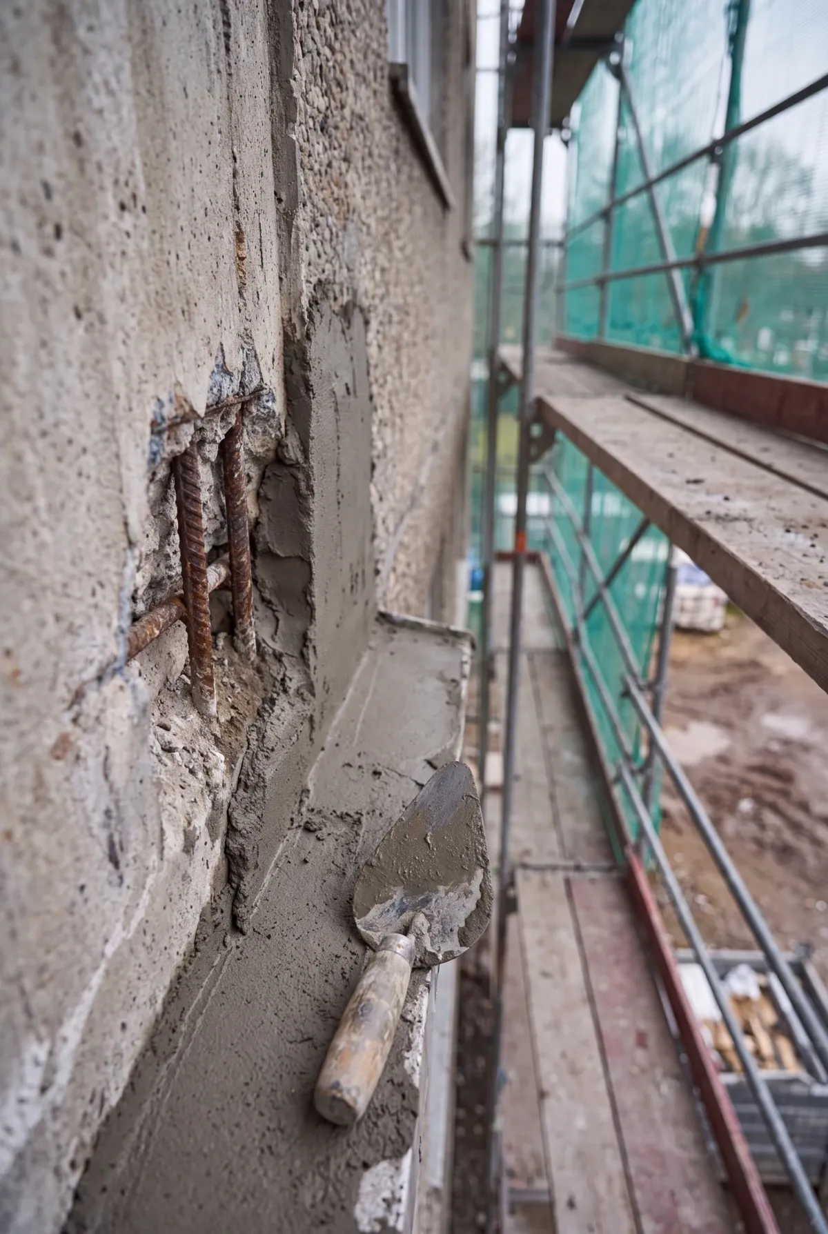 Freigelegte Bewehrung neben frischem Reparaturmörtel